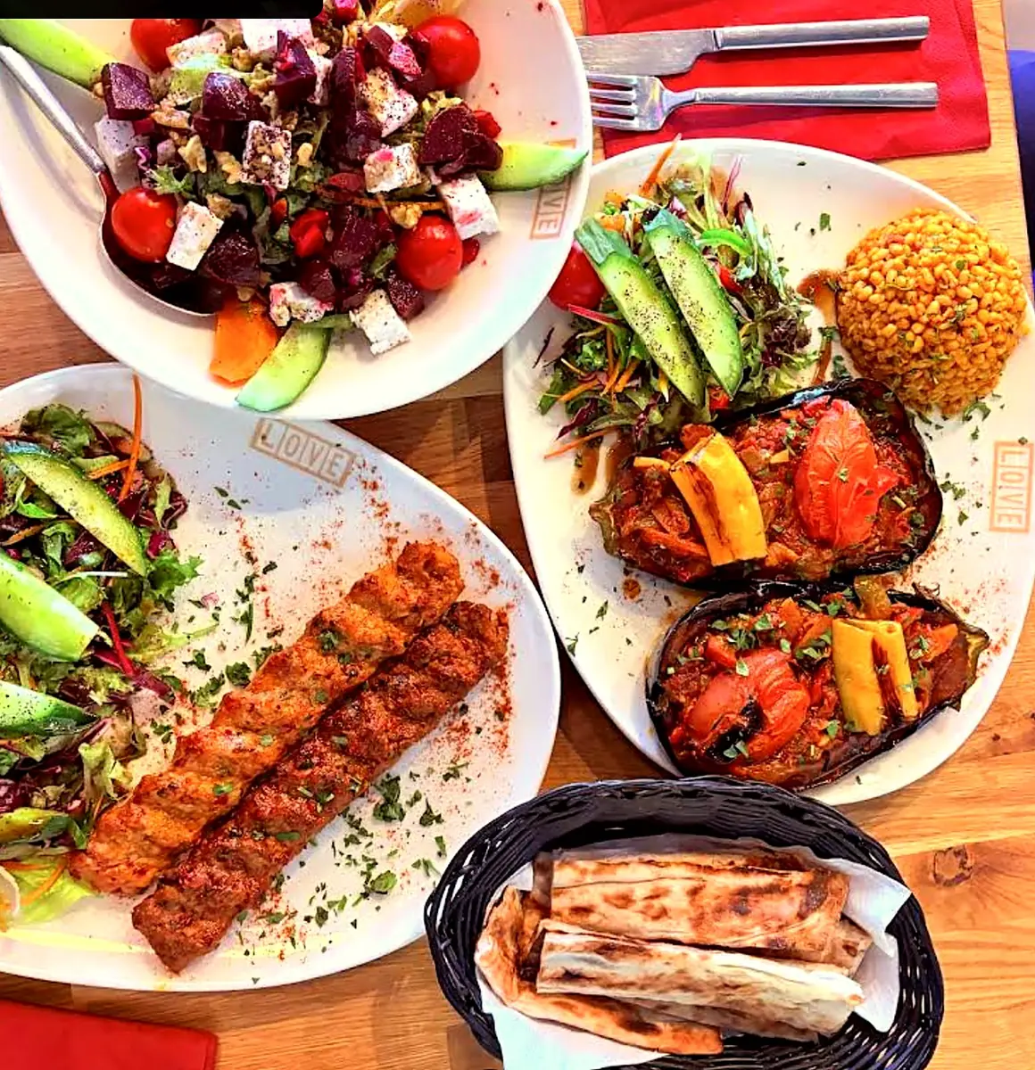 Table spread of adana kebab from the charcoal grill, beetroot salad, stuffed aubergine, bulgur and pide