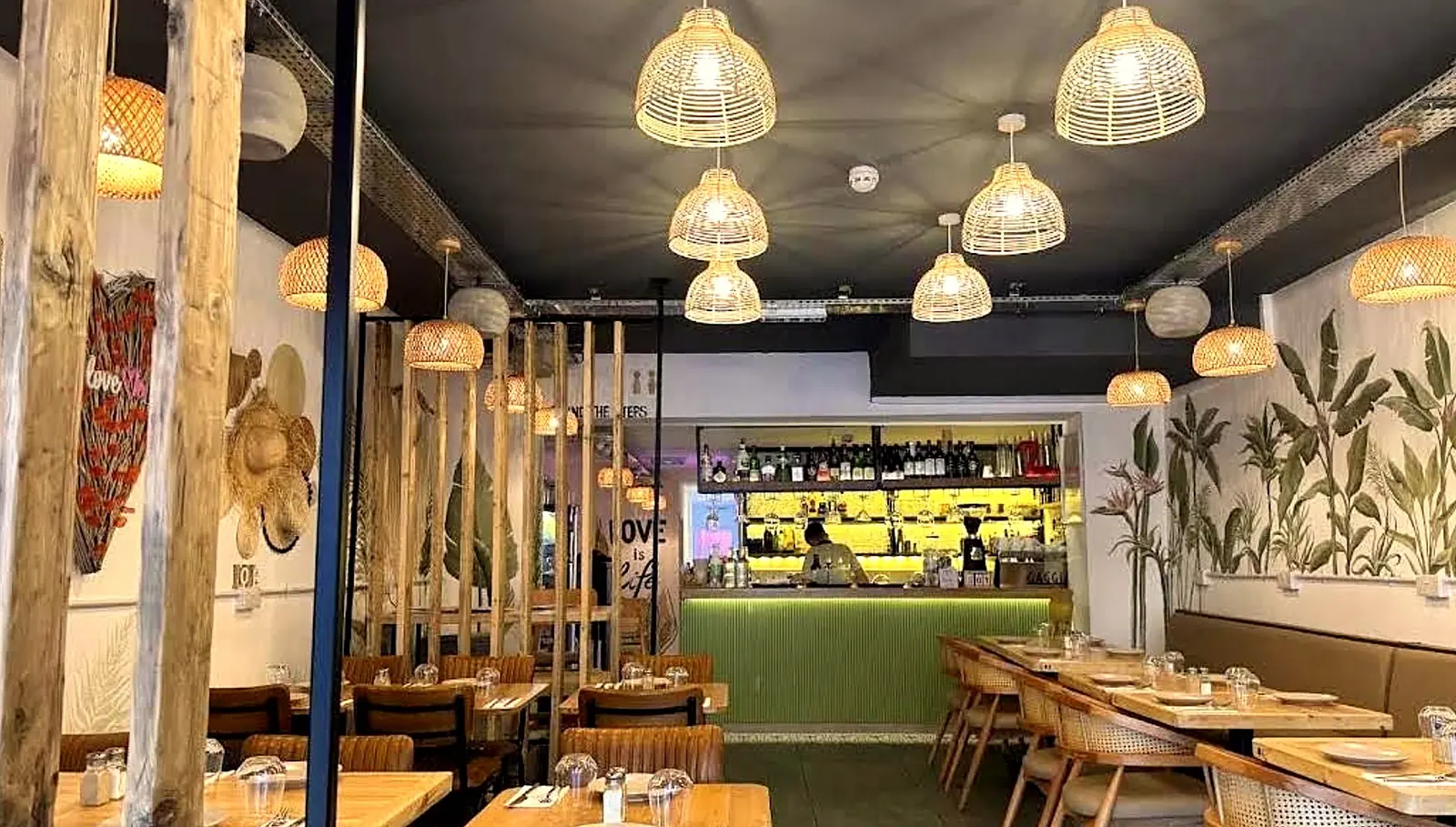 The dining room and green-tiled bar under rattan pendant lamps
