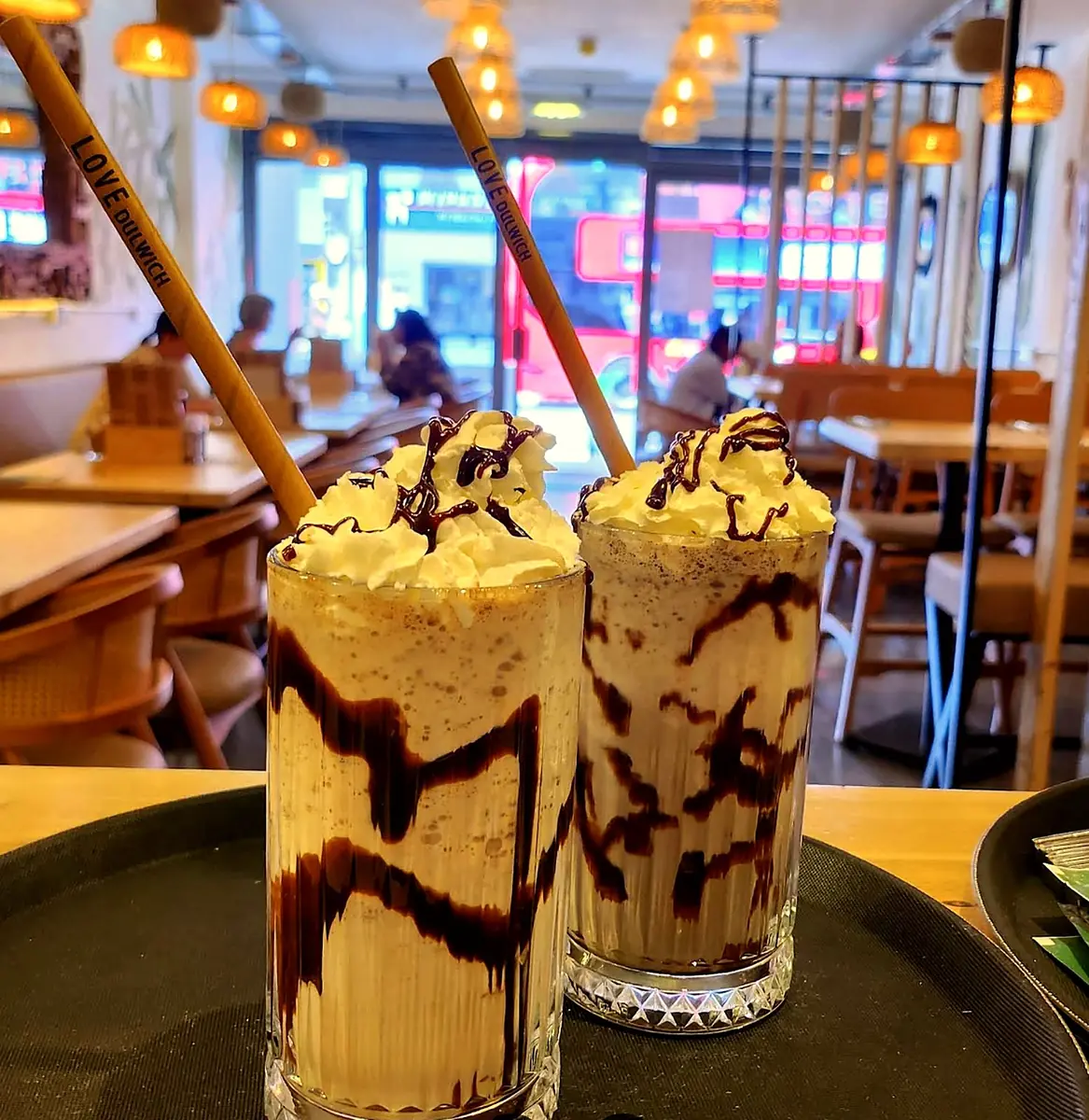 Two milkshakes with whipped cream and chocolate drizzle