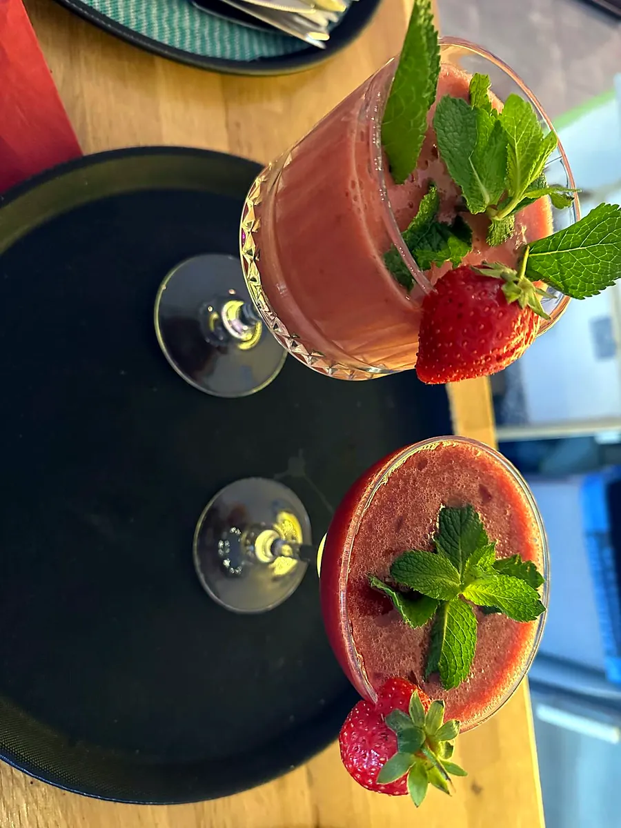 Two strawberry cocktails garnished with fresh mint and strawberries