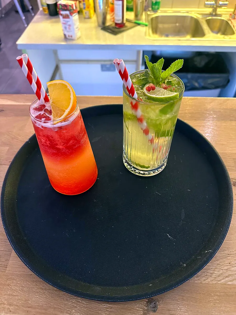 A red fruit cocktail and a mojito with striped straws